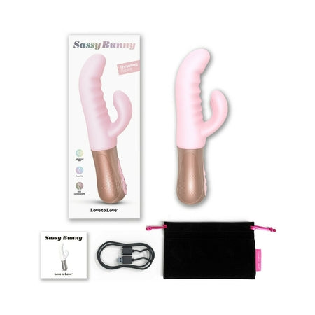 A pink and beige rabbit vibrator with dual stimulation design, displayed alongside its box and a black storage pouch. The product has a curved silicone shaft and a smaller attachment for clitoral stimulation.