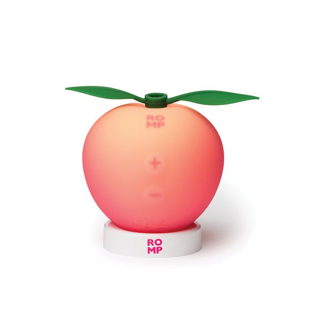 A peach shaped massager in its usb rechargeable docking station