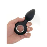 Black silicone butt plug held in a hand on a white background